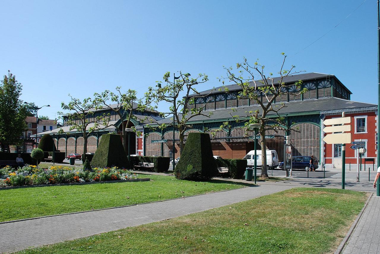 Bâtiment de marché avec toit en zinc, jardins et arbres en plein air à Toulouse.