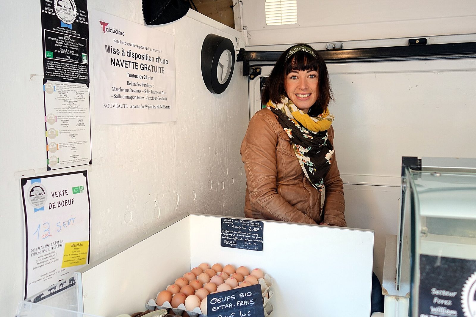 Vendeuse devant un étal avec des œufs bio et des panneaux d'information